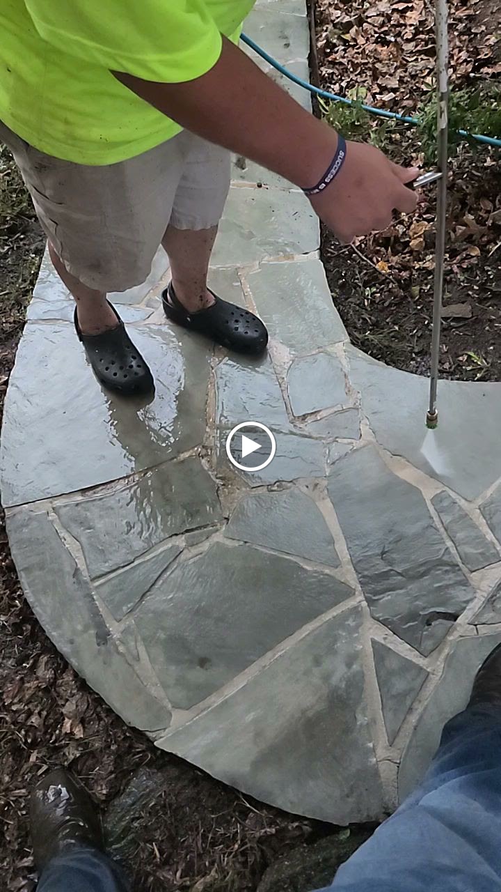 Video preview showing a worker pressure washing a stone walkway